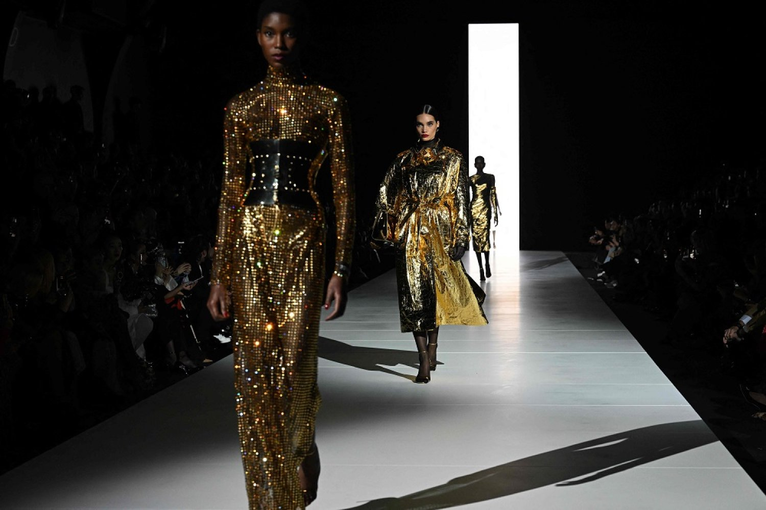 Models wearing glamorous, shiny gold dresses walk the runway, illustrating the fusion of Hollywood and haute couture.